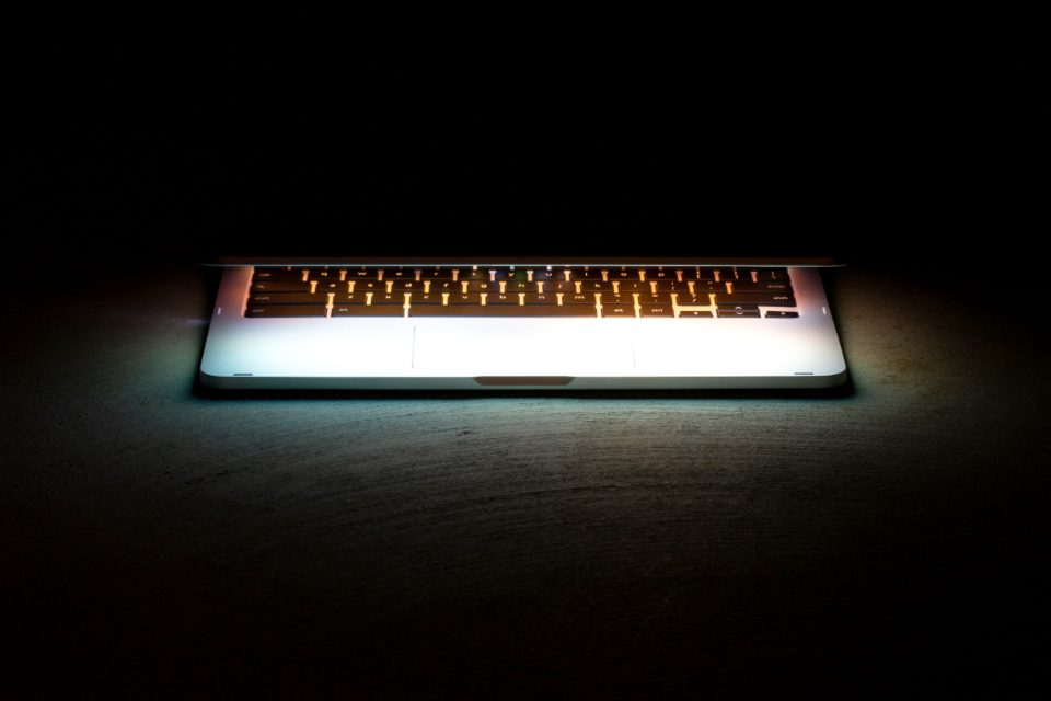 Teclado de um notebook iluminado no escuro